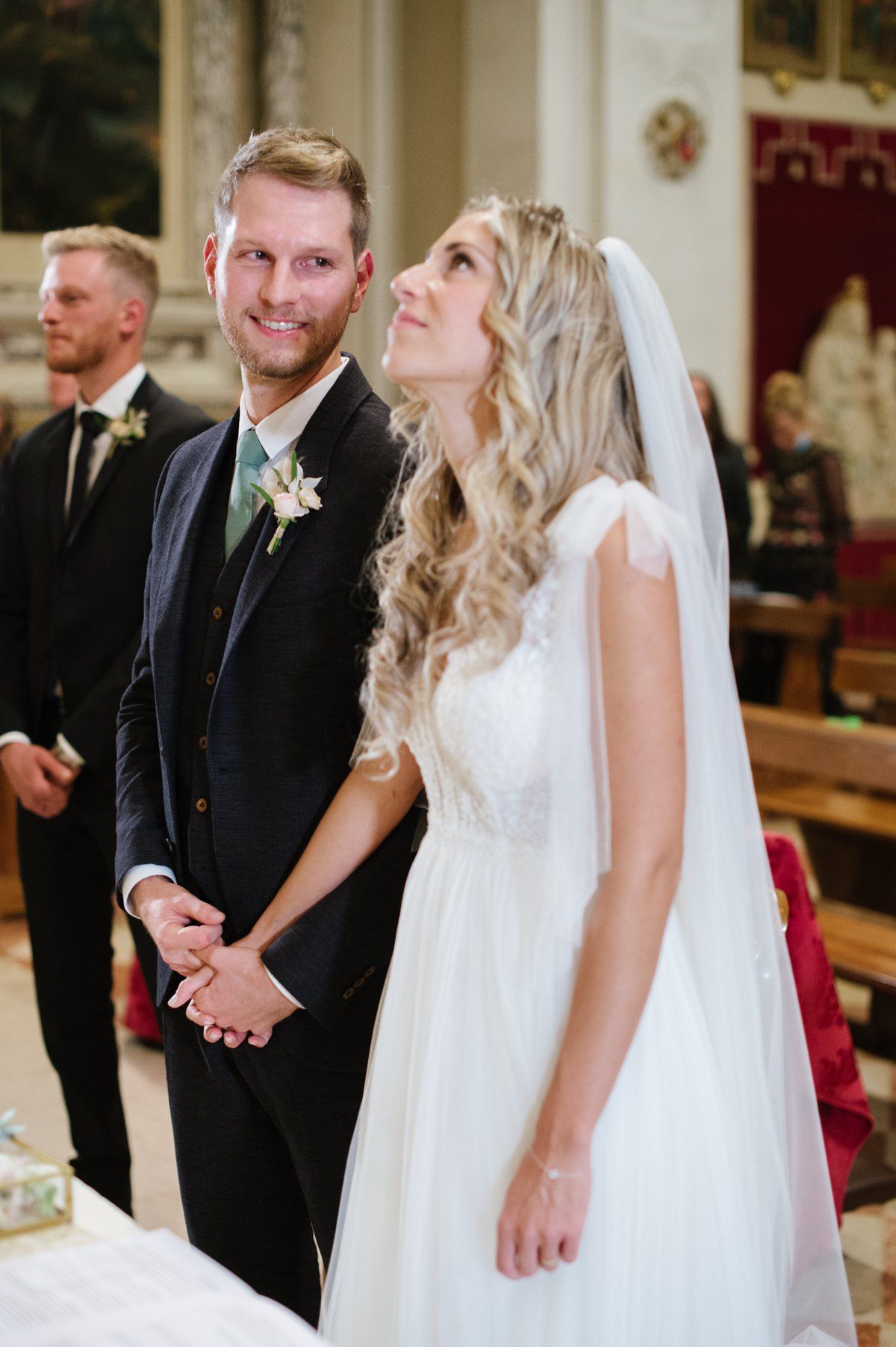 A joyful couple shares a light moment during their wedding ceremony in a beautiful church.
