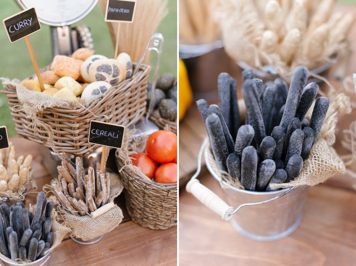 Rustic wedding appetizer display with breadsticks and snacks arranged in woven baskets on wooden table.