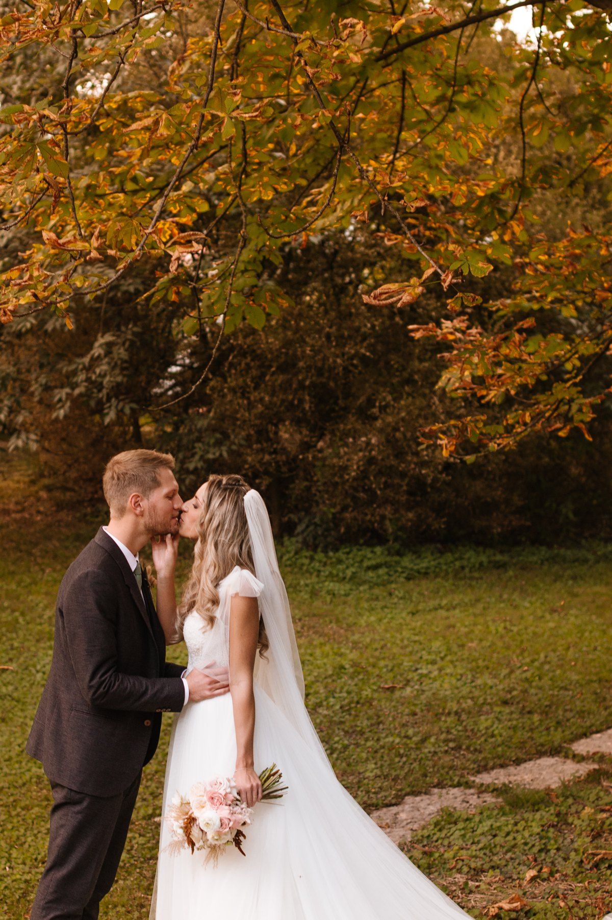 Romantic wedding portrait beneath golden autumn leaves.