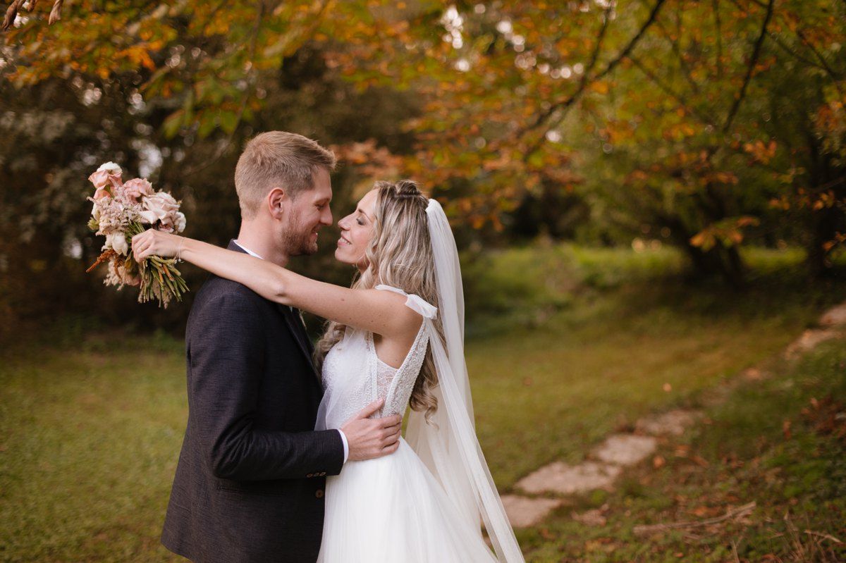 A tender wedding moment captured under autumn foliage.