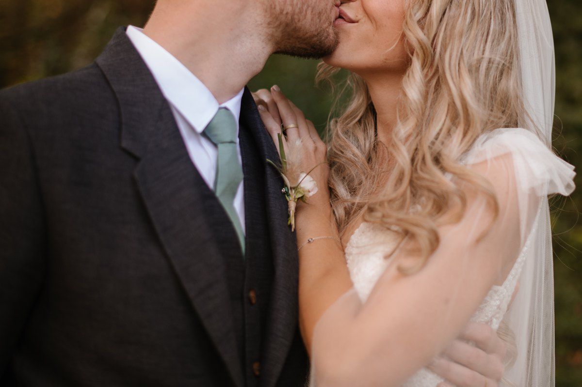 Romantic close-up of newlyweds sharing an intimate kiss in their wedding attire.