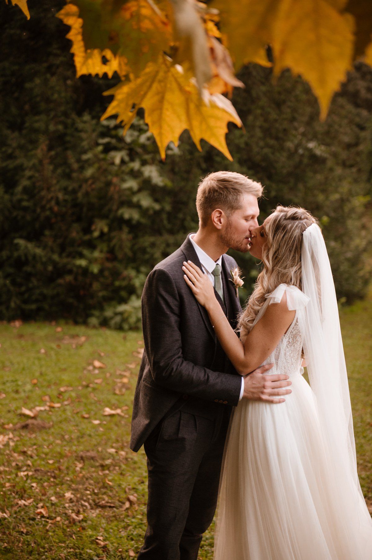 Intimate wedding portrait under golden autumn leaves.