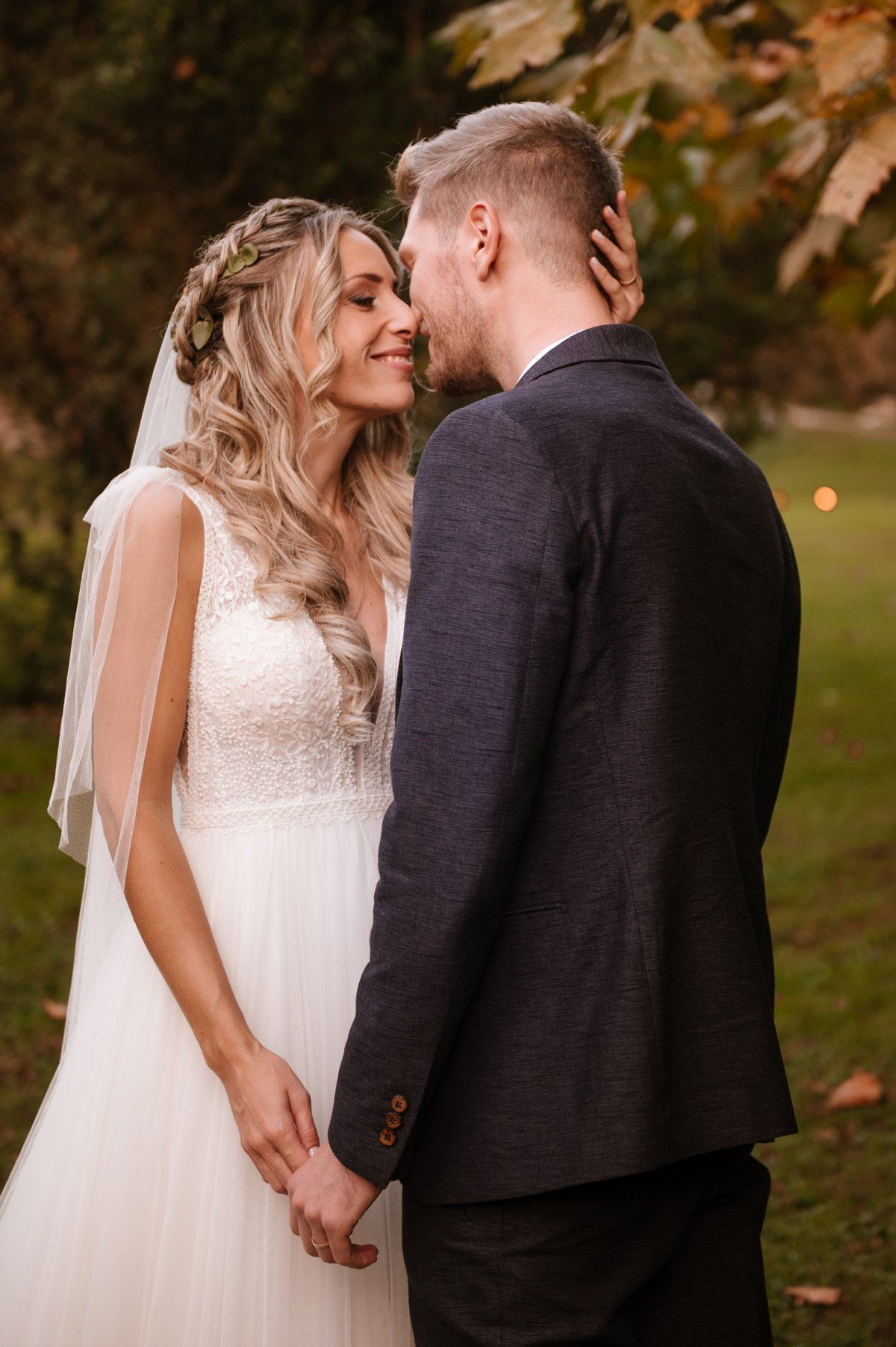 Romantic wedding moment captured between newlyweds in an autumn garden setting.