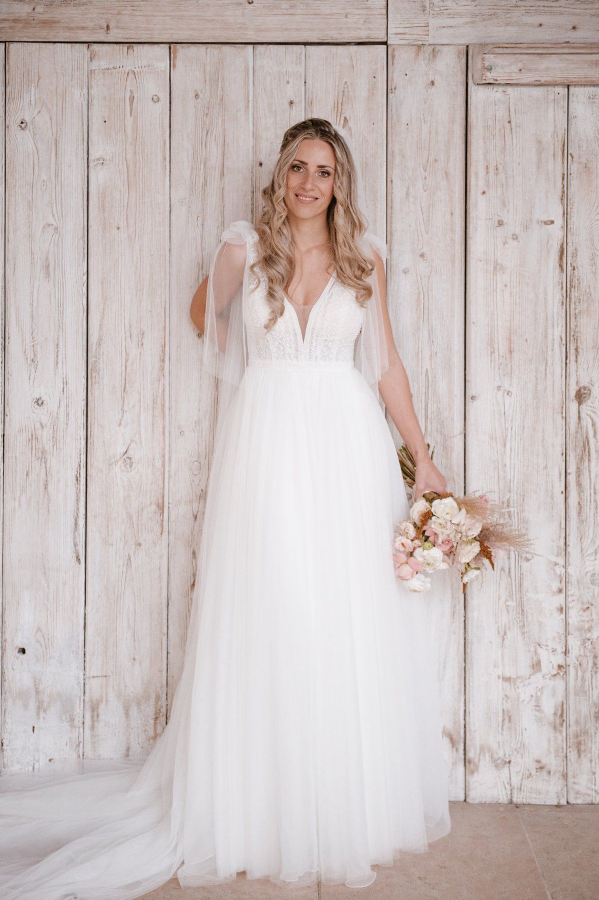 Full-length bridal portrait against weathered white wooden doors.