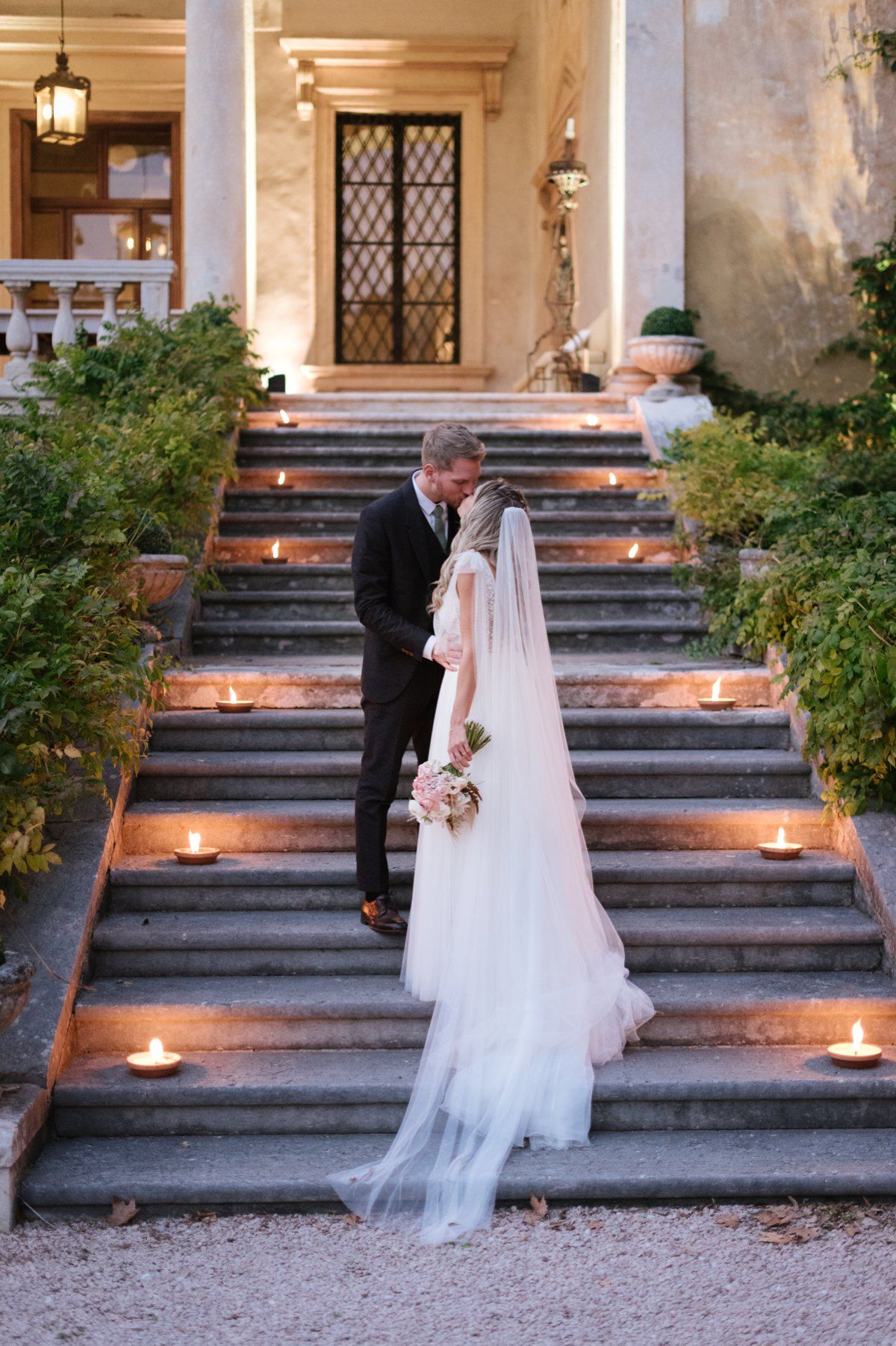 Romantic moment between couple on candlelit steps of Italian villa at dusk.