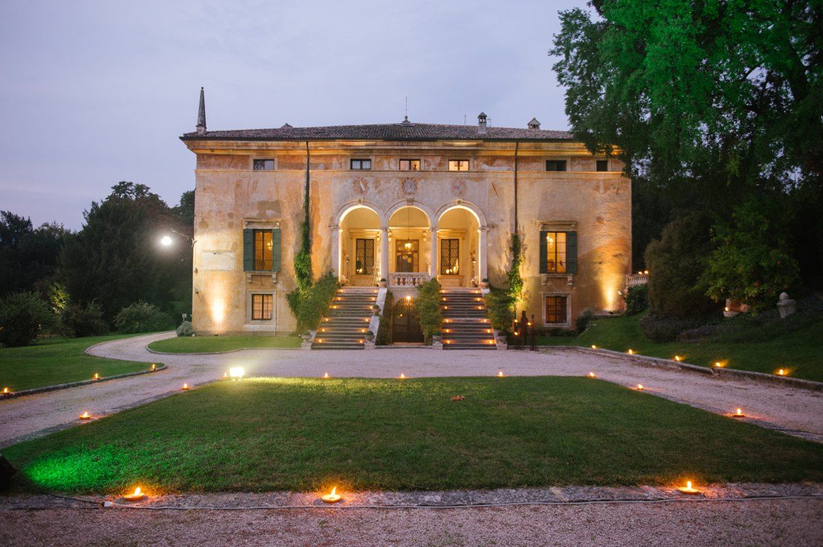 Elegant villa illuminated at dusk with grand staircase and landscaped pathway lined with glowing lights.