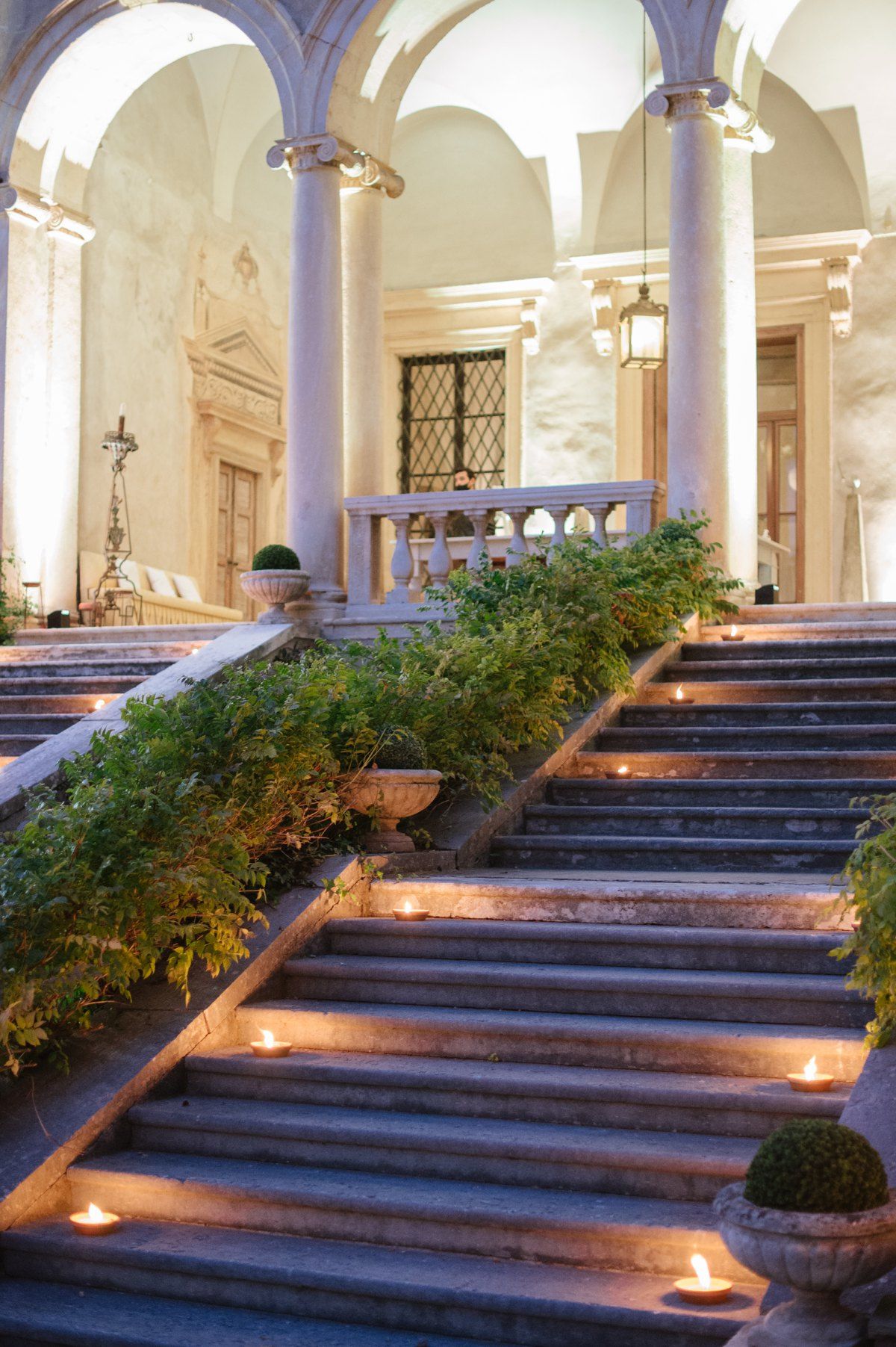 Grand archway entrance with illuminated stone steps decorated with greenery and candles.