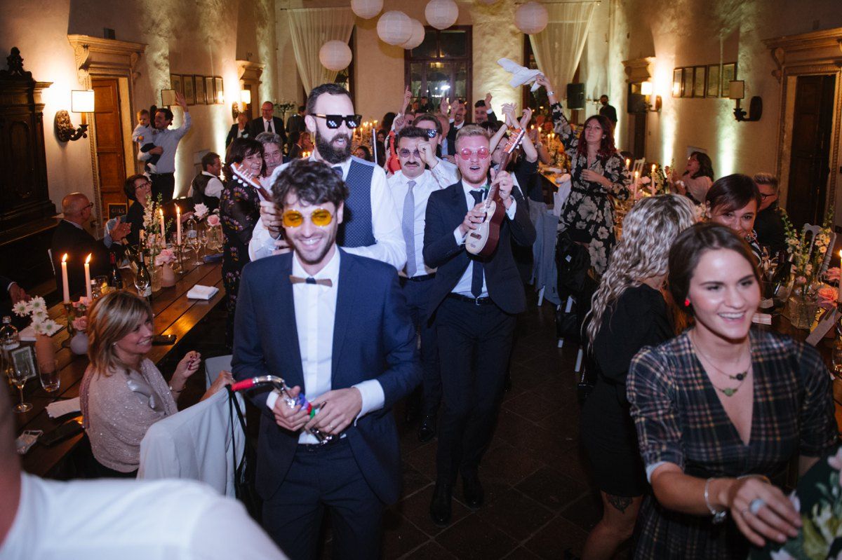 Wedding guests dance and celebrate in an elegantly lit venue with balloons and candles.