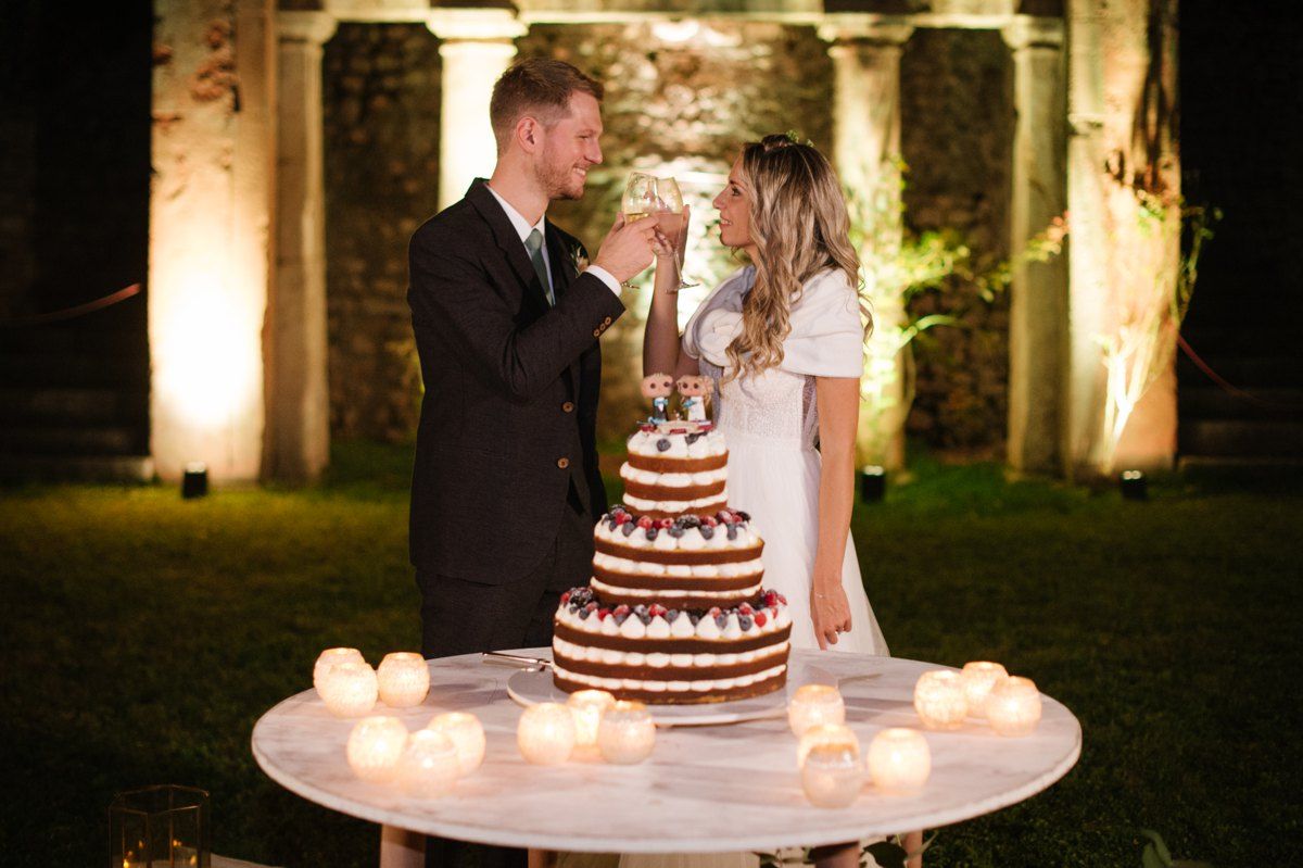 A romantic moment shared during cake cutting with illuminated ruins in background.