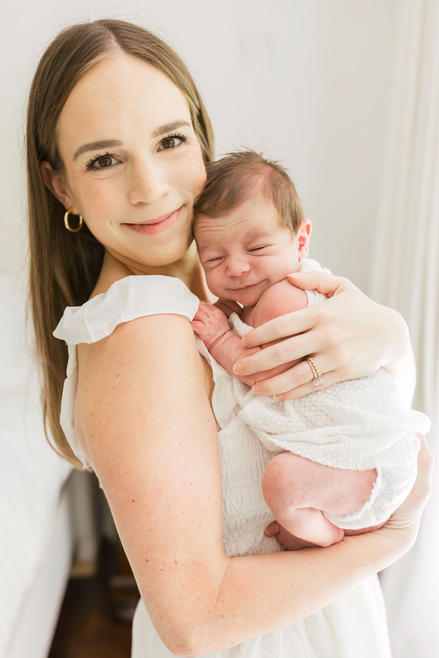 Joyful moment with smiling parent holding happy newborn baby.