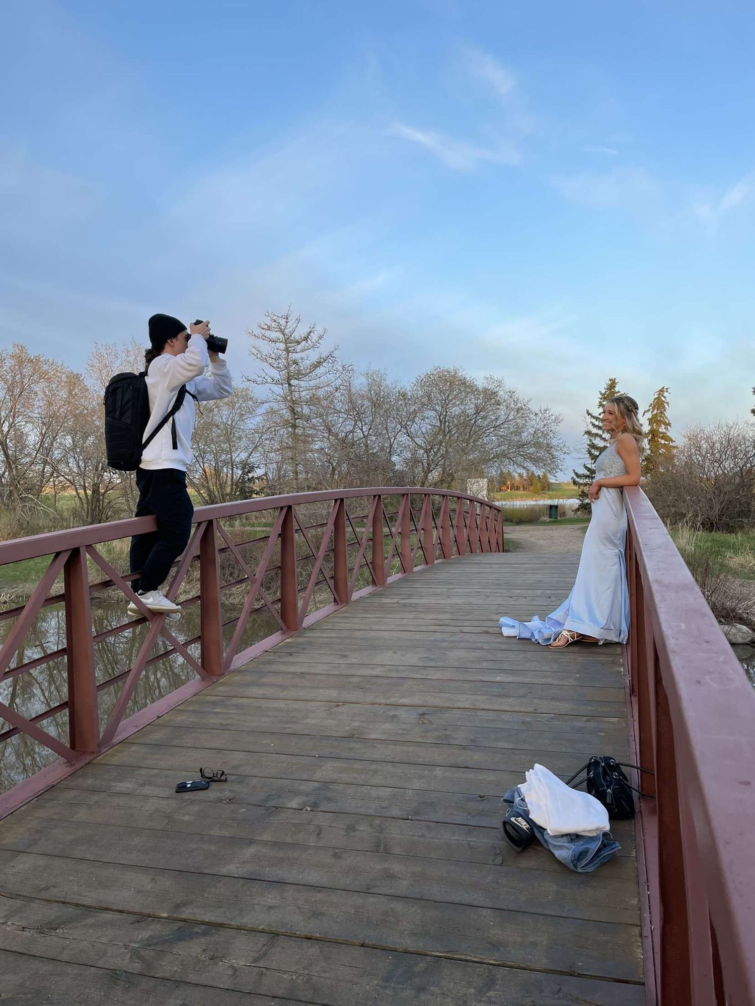 Photographer capturing a photo shoot on a wooden bridge during a sunny day.