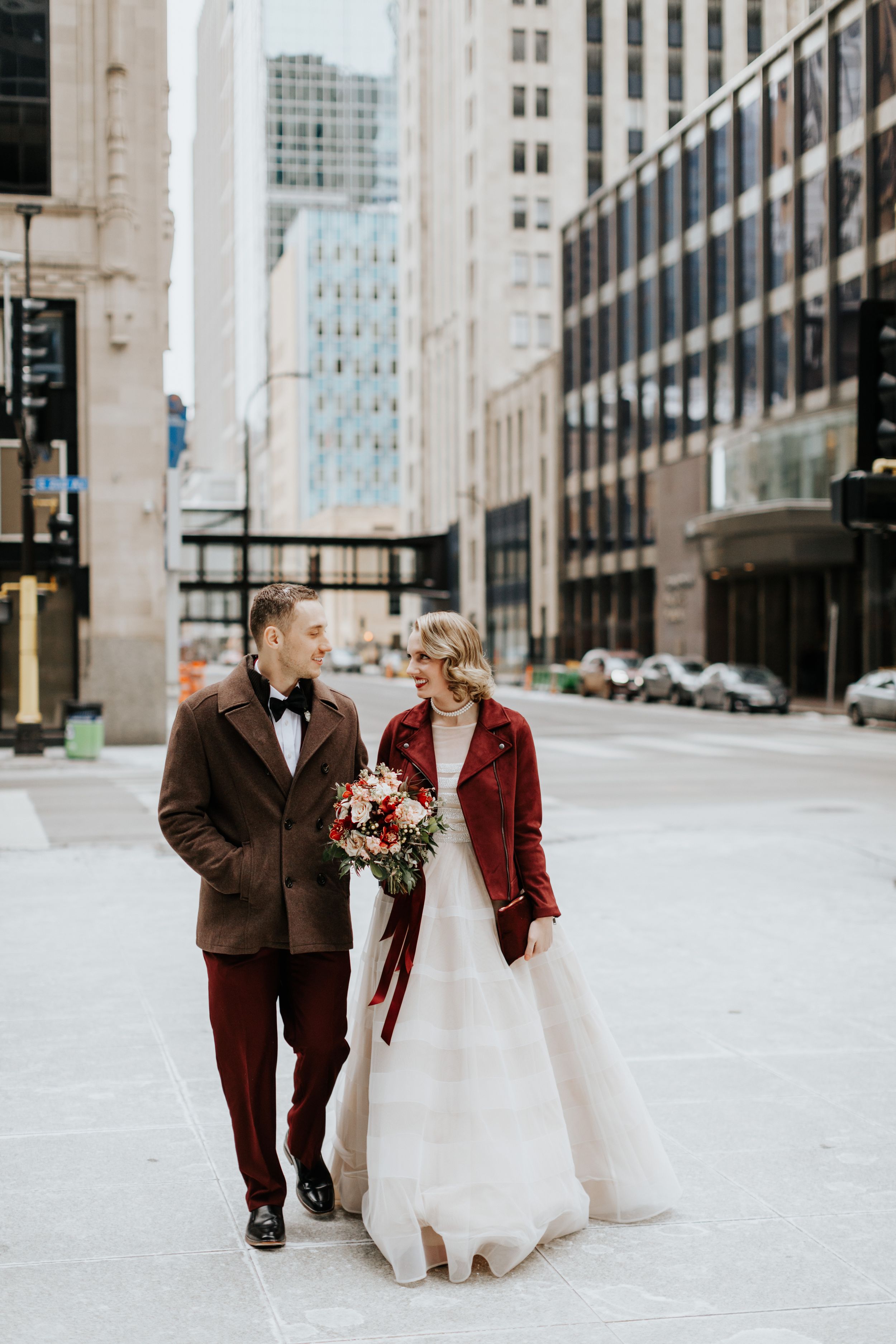 Couple in formal wear walking through urban city street with skyscrapers.
