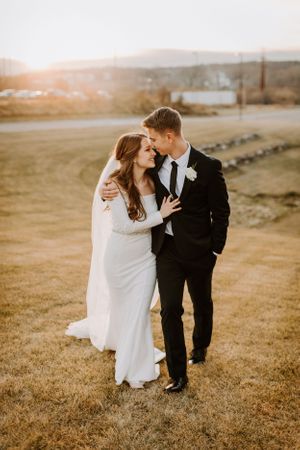 Intimate wedding portrait at golden hour with mountains and countryside in background.