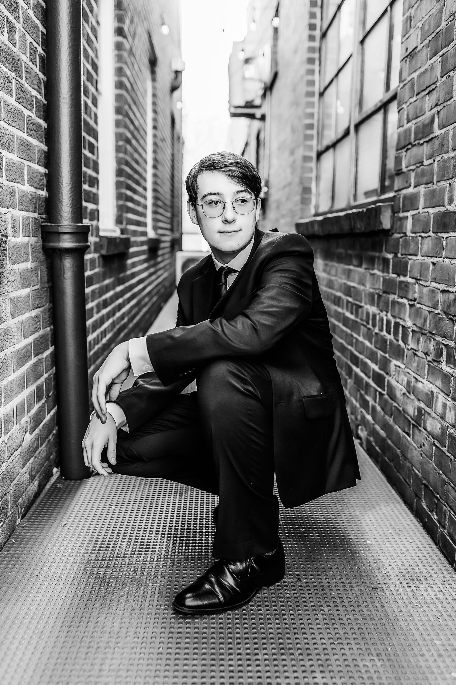 Professional portrait in urban alley with brick walls and industrial details.