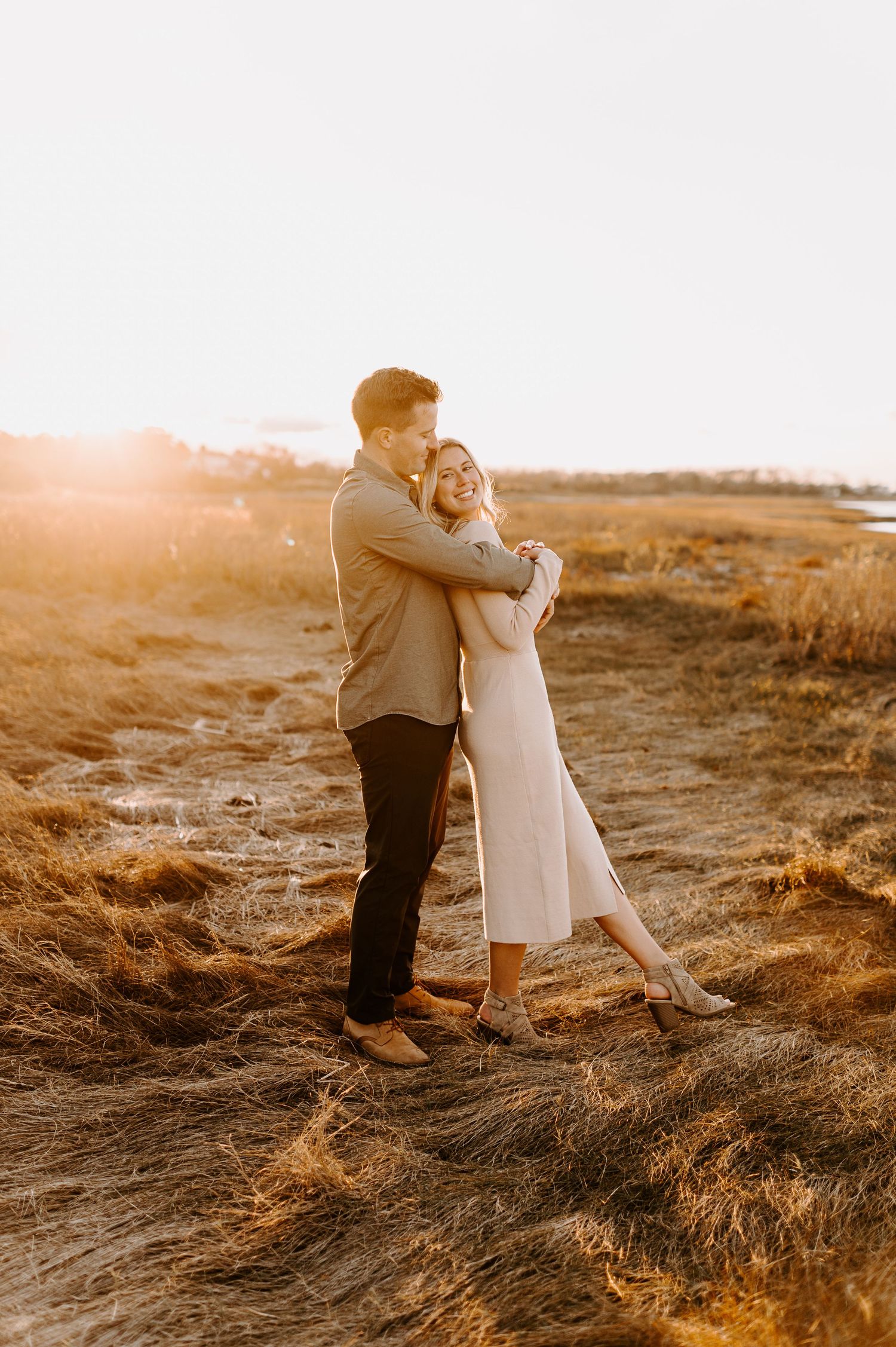 Two people share an intimate dance in a field bathed in golden sunset light.