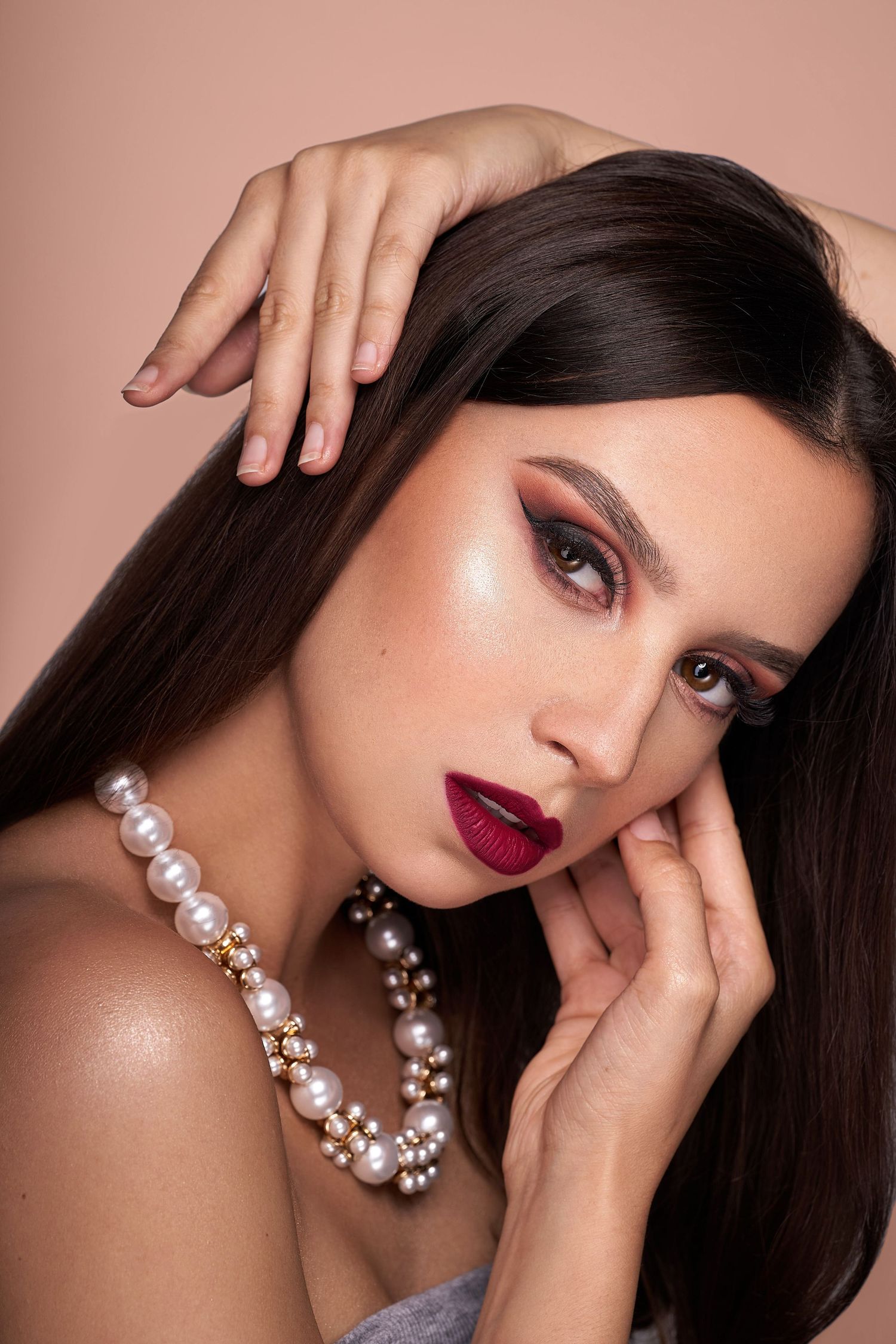 Elegant beauty portrait with dark lipstick, pearl necklace and dramatic makeup.
