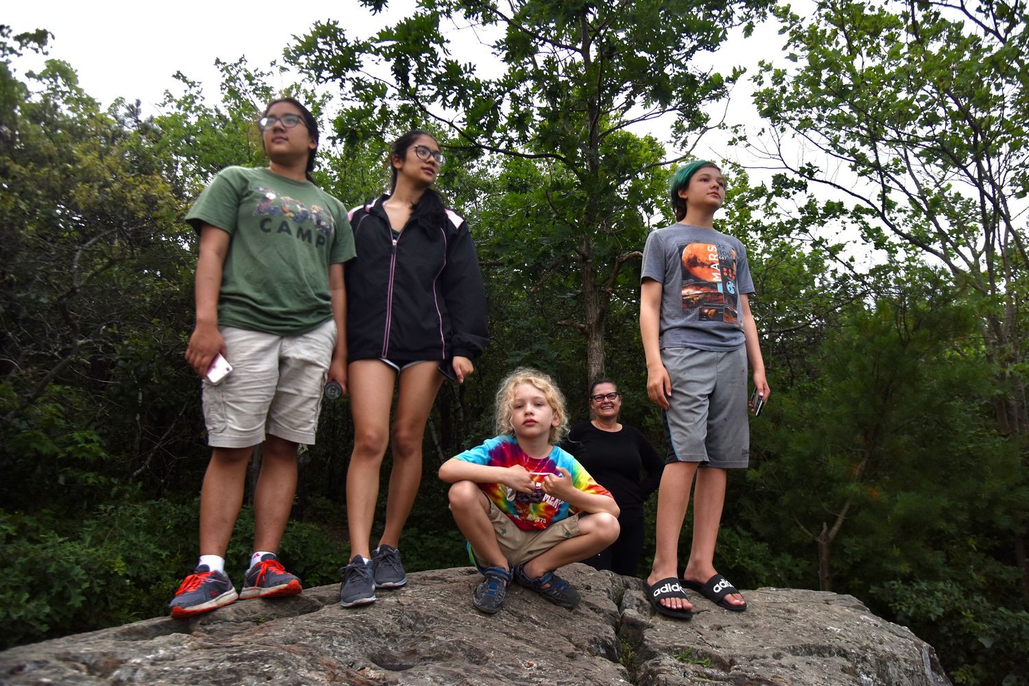 Group poses together on rocky outcrop during hiking adventure.