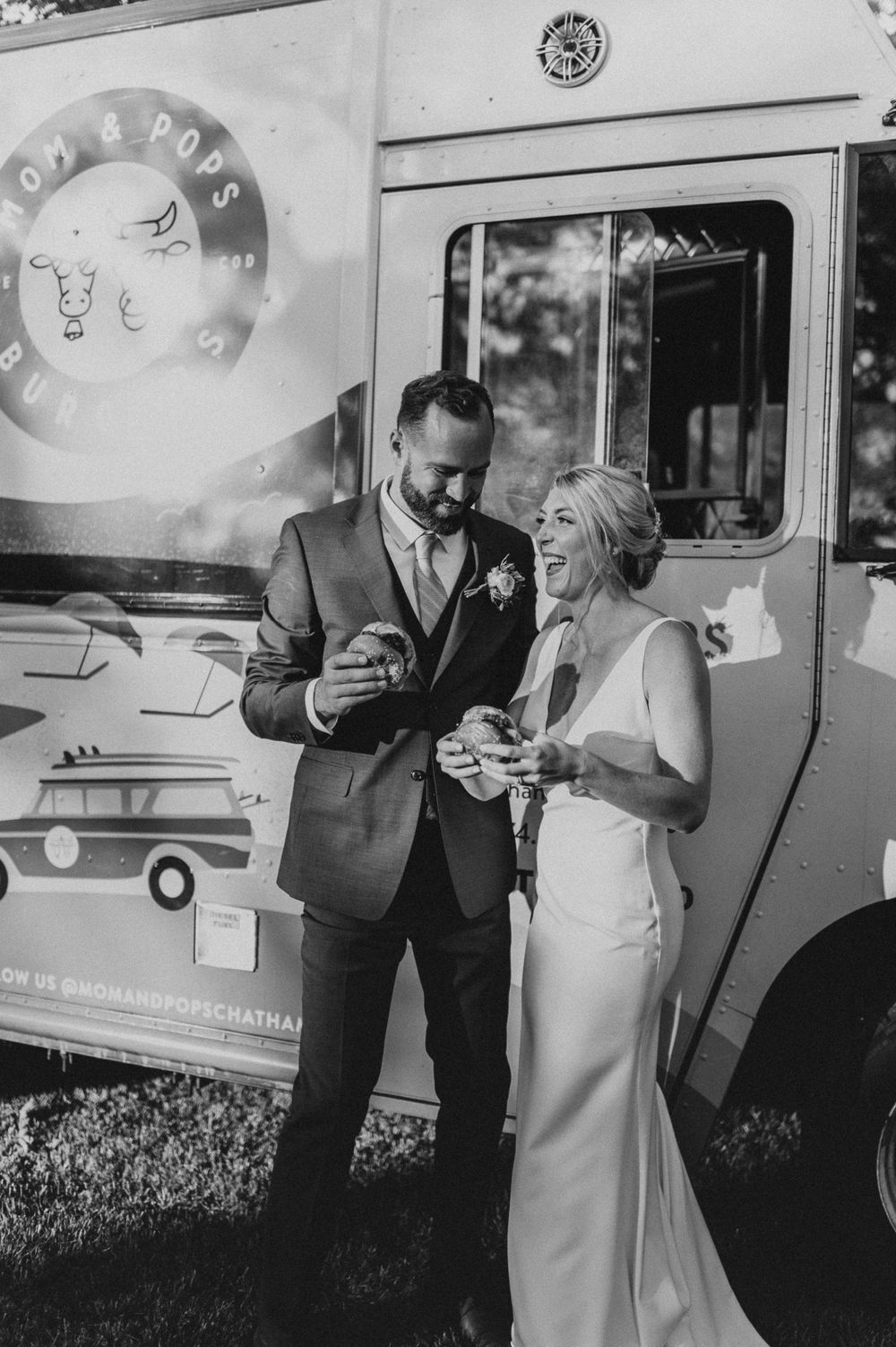 A black and white photo shows a couple enjoying food from a retro food truck.