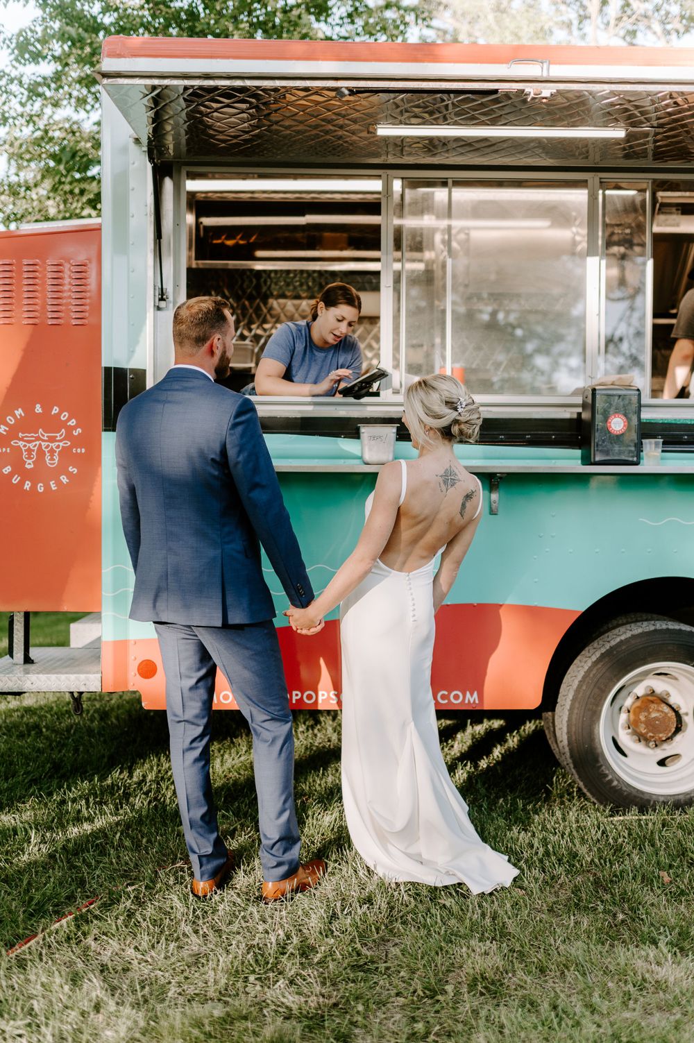 A couple walks up to place their order at a mint and coral colored food truck.