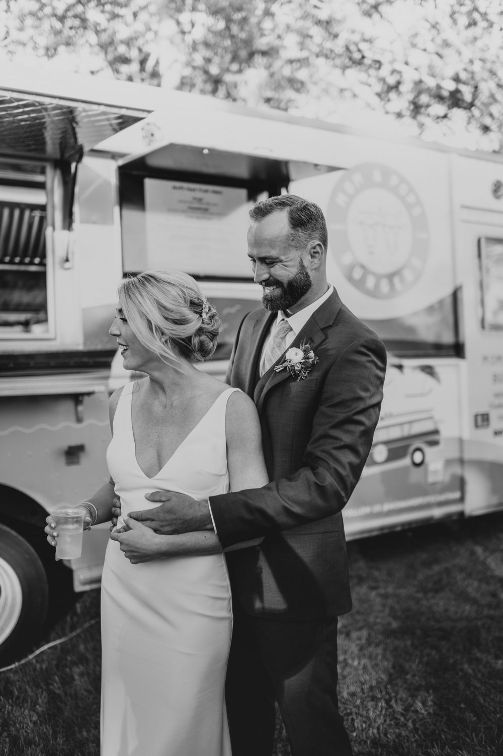 Black and white photo of couple enjoying food together by vintage truck.