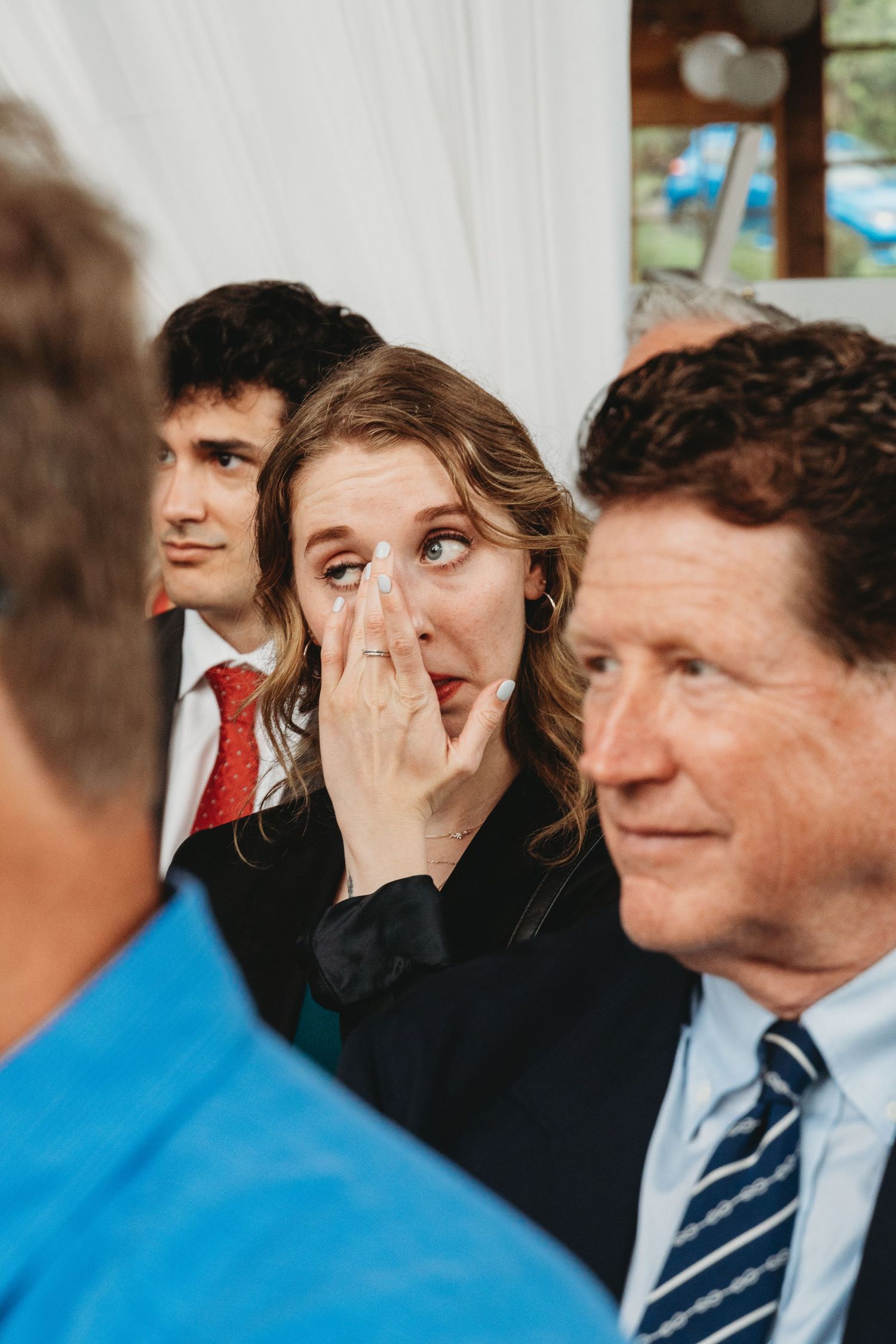 Emotional wedding ceremony moment captured in front of white draped backdrop.