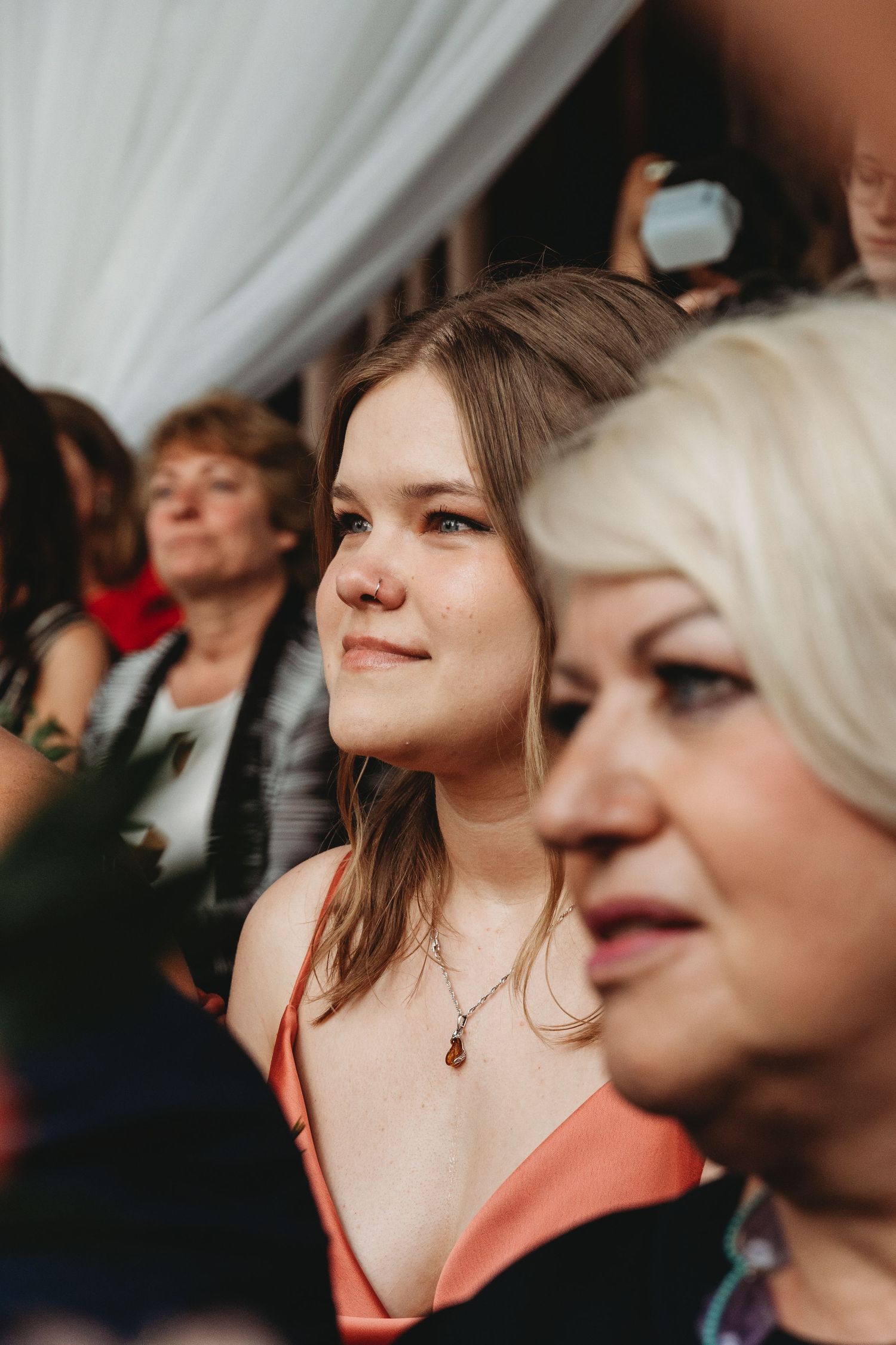 Wedding guests watching ceremony in rustic venue with white draping.