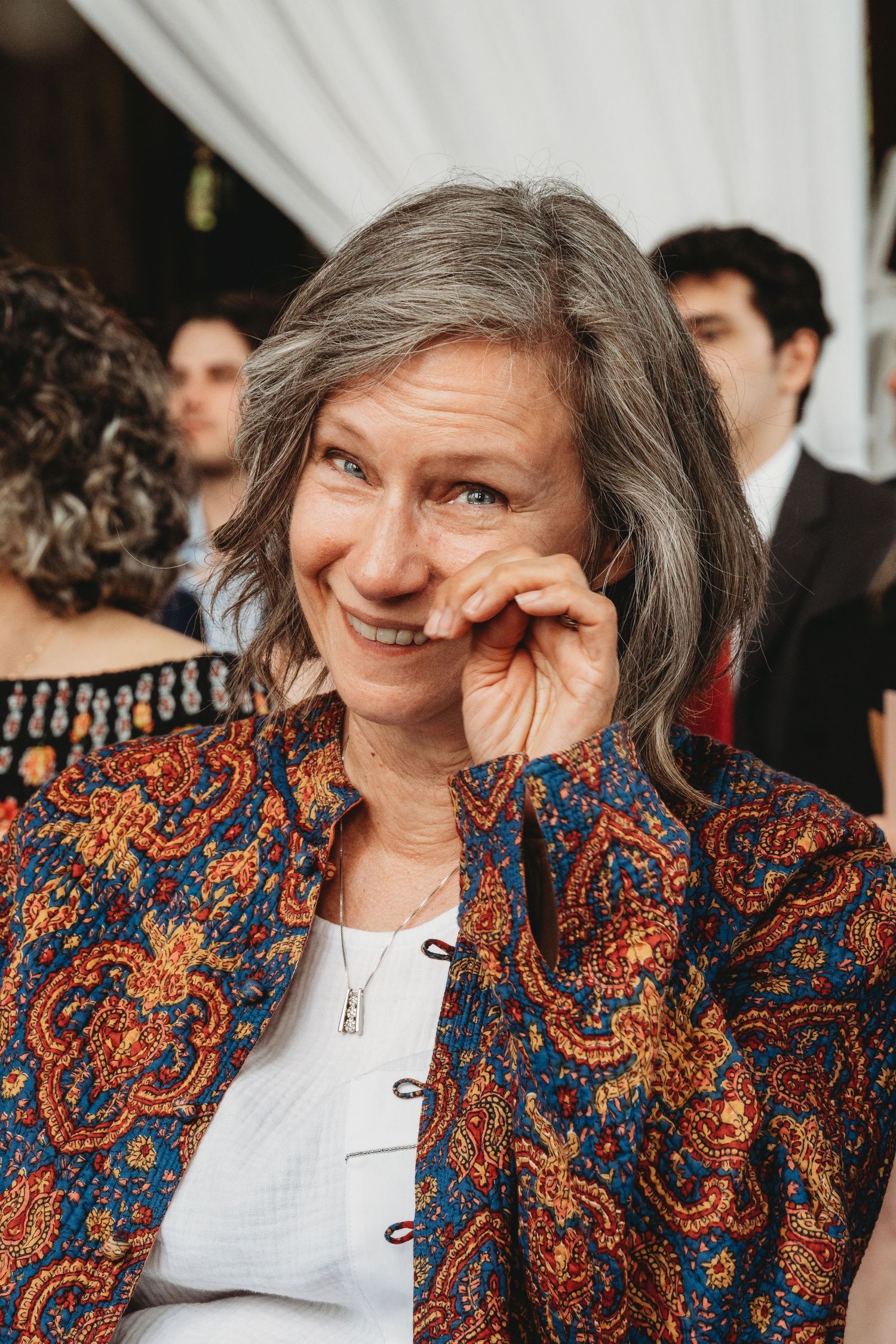 Wedding guest in colorful patterned jacket enjoying emotional moment at celebration.
