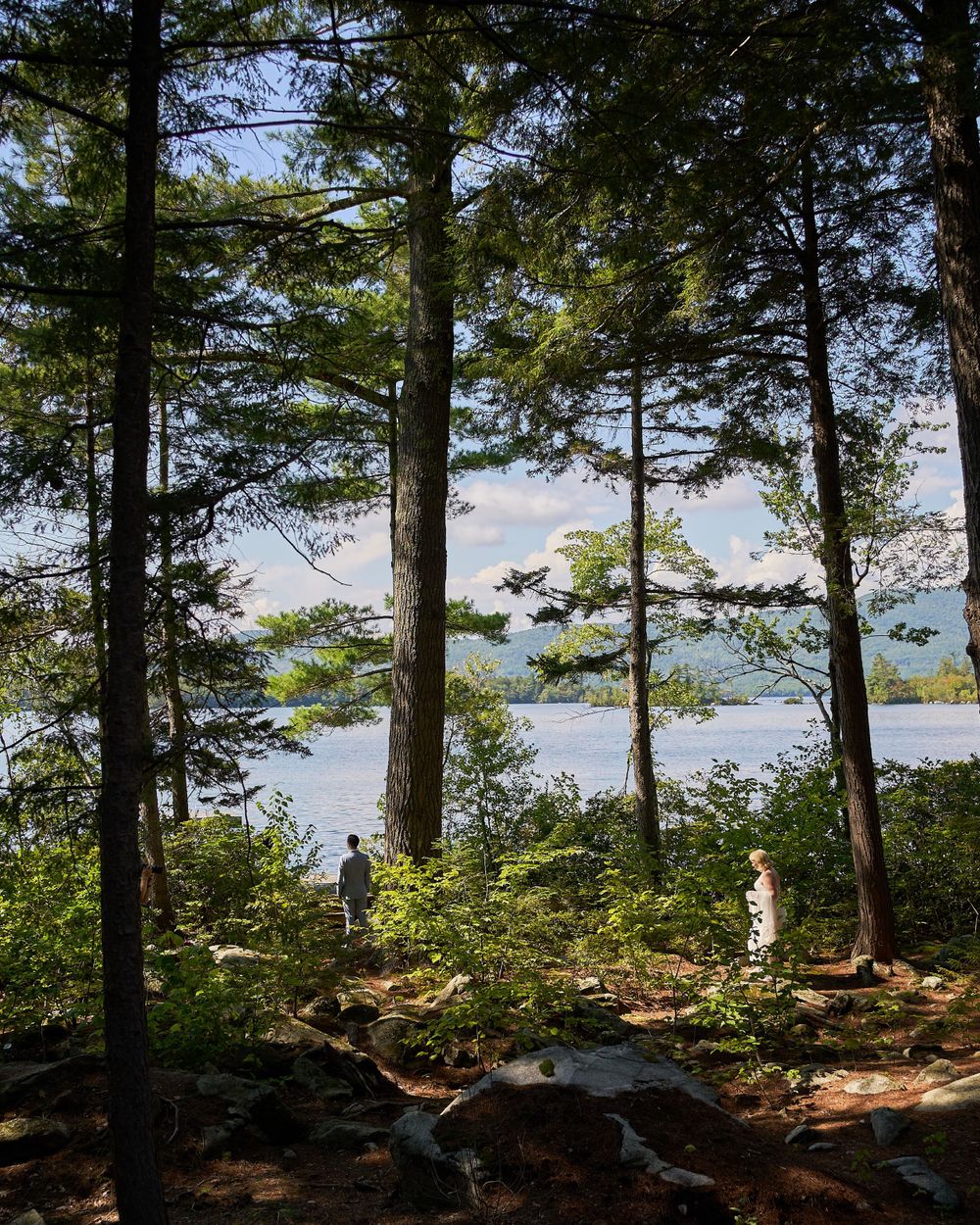 Bride approaches groom for first look in idyllic woodland lakeside setting
