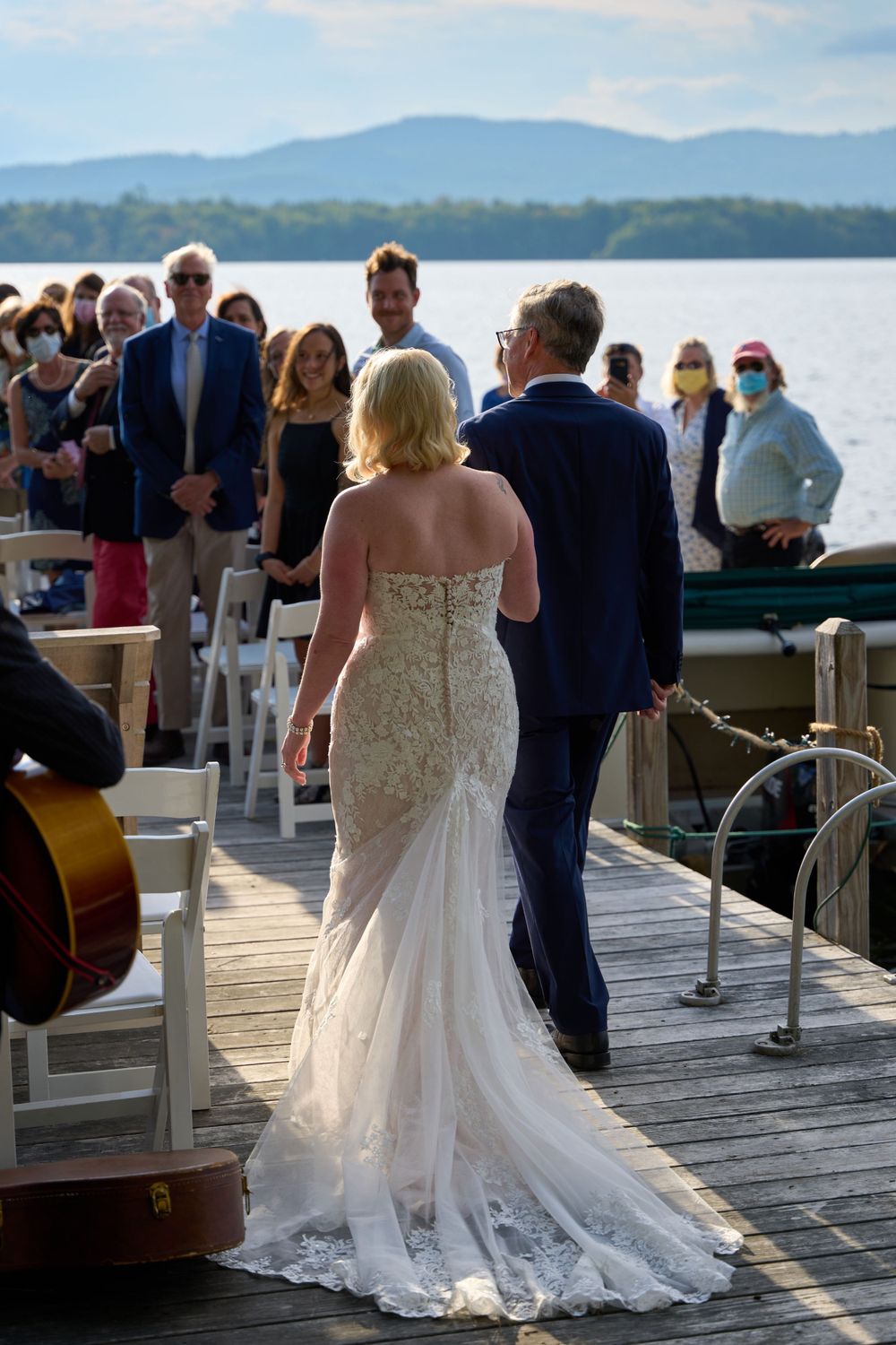 Bride escorted by her father approaches ceremony on Squam Lake pier late day light