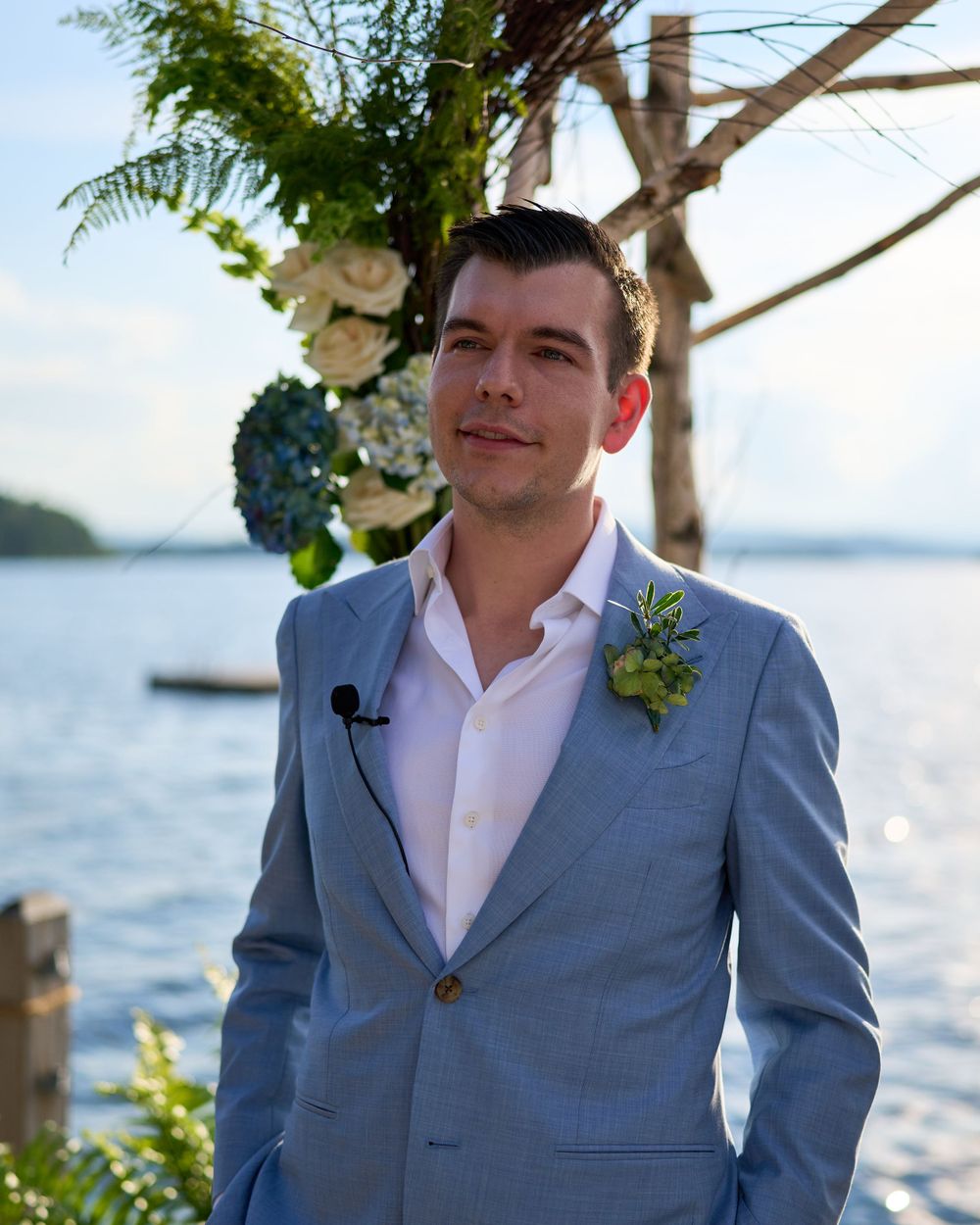 Handsome, dark haired groom watches his bride approach the ceremony site Squam Lake