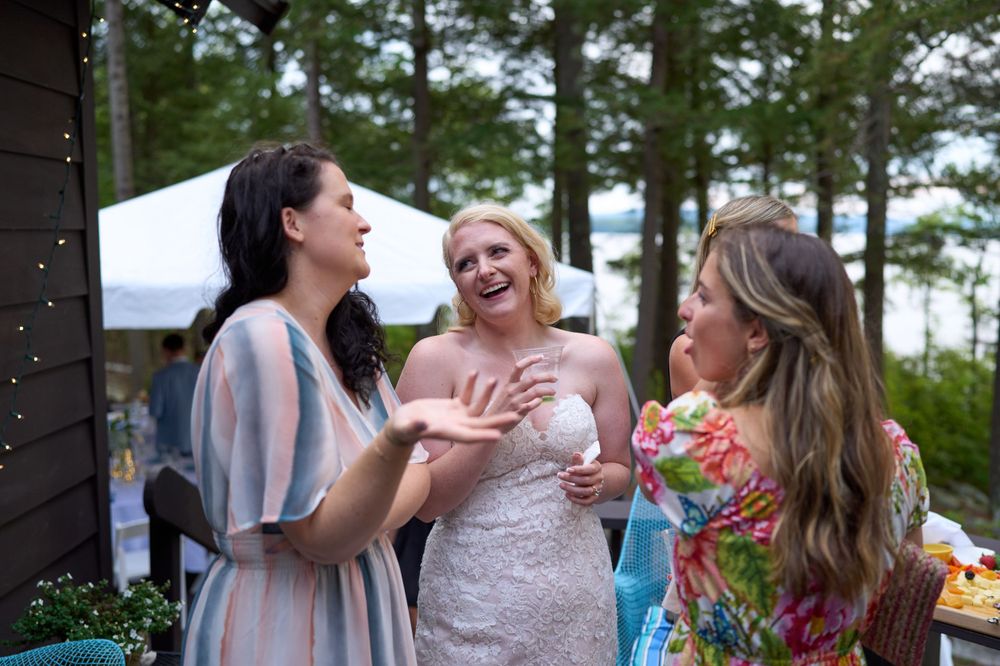 Bride laughs with her reception guests after lakeside ceremony