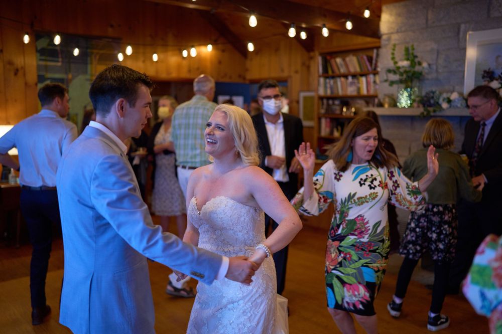Gaily lit lakeside living room illuminates dancing newlyweds and wedding guests