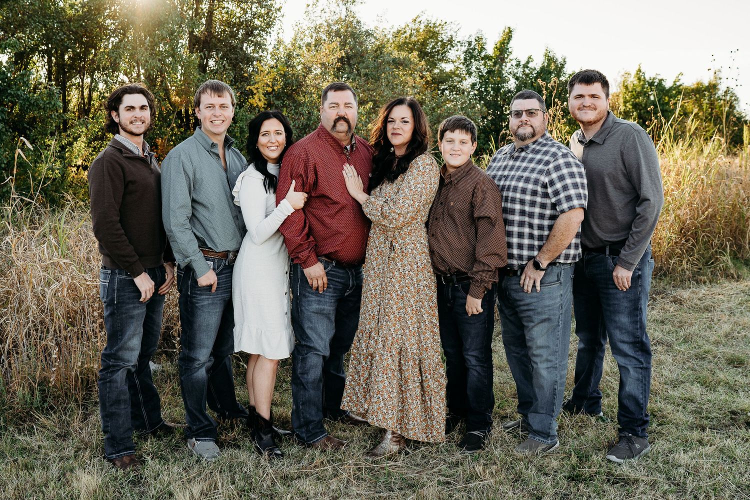 A large family group posing together outdoors at sunset in casual attire.
