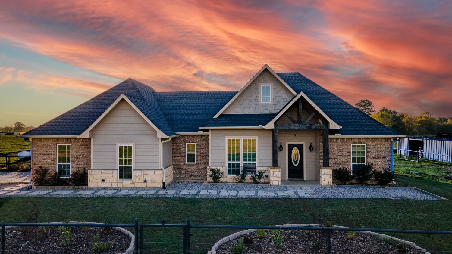 Row of modern suburban homes silhouetted against a vibrant sunset sky.