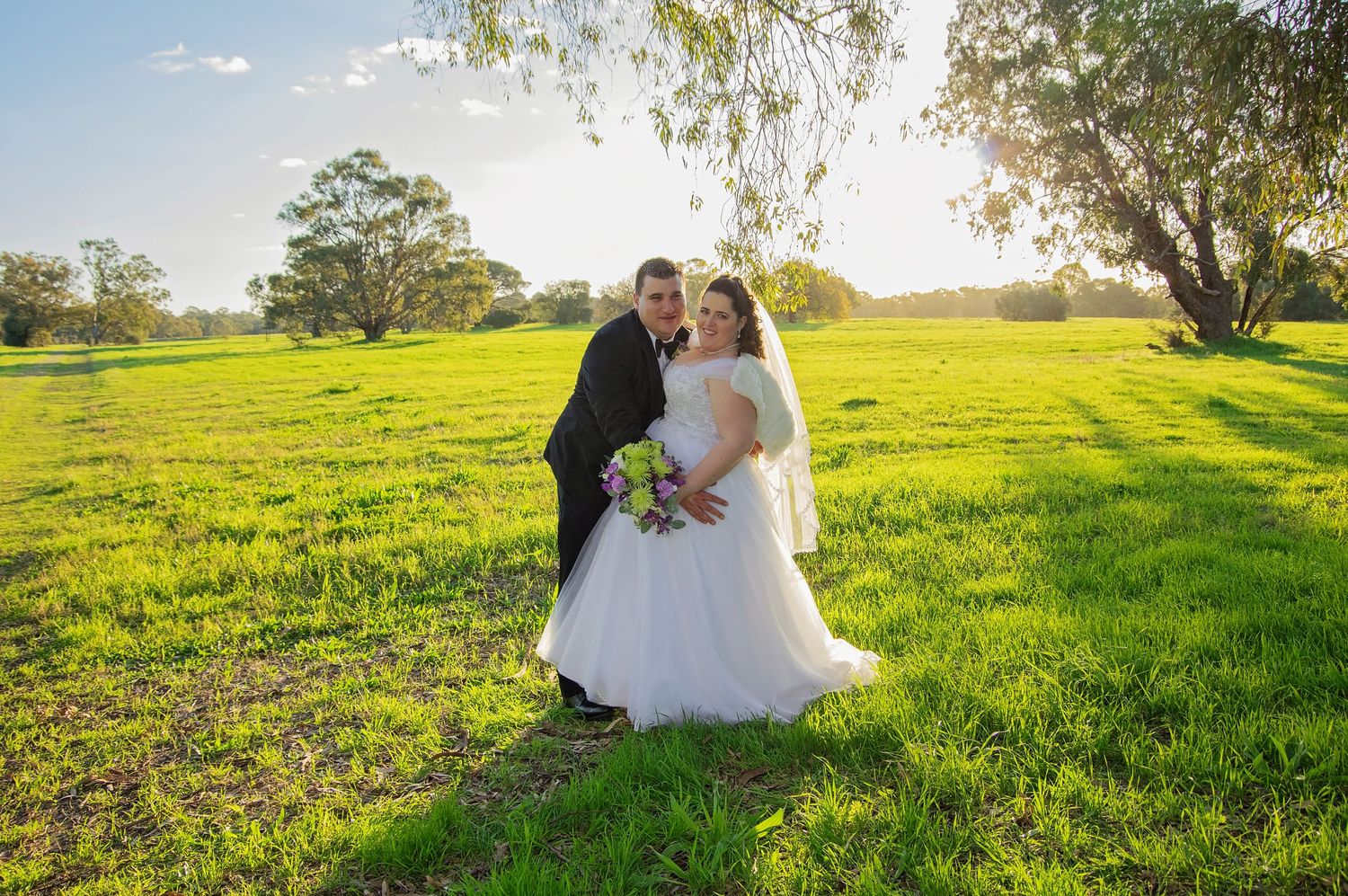 bride and groom posed in grass field