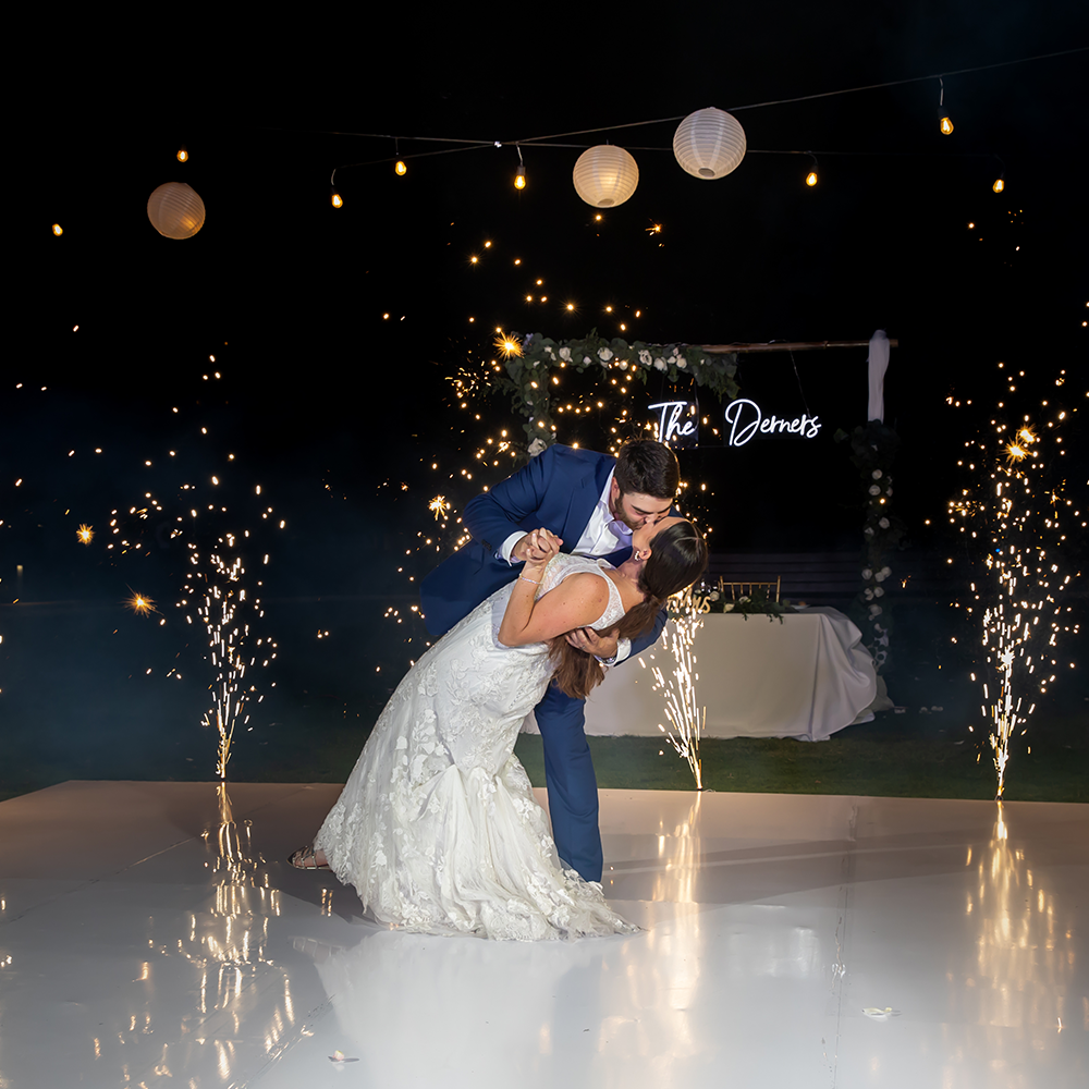 Wedding couple shares romantic dip dance under paper lanterns and sparklers during evening reception.