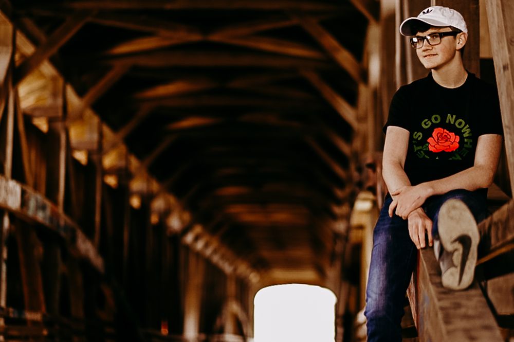 Side view of person in casual wear sitting in rustic wooden corridor.