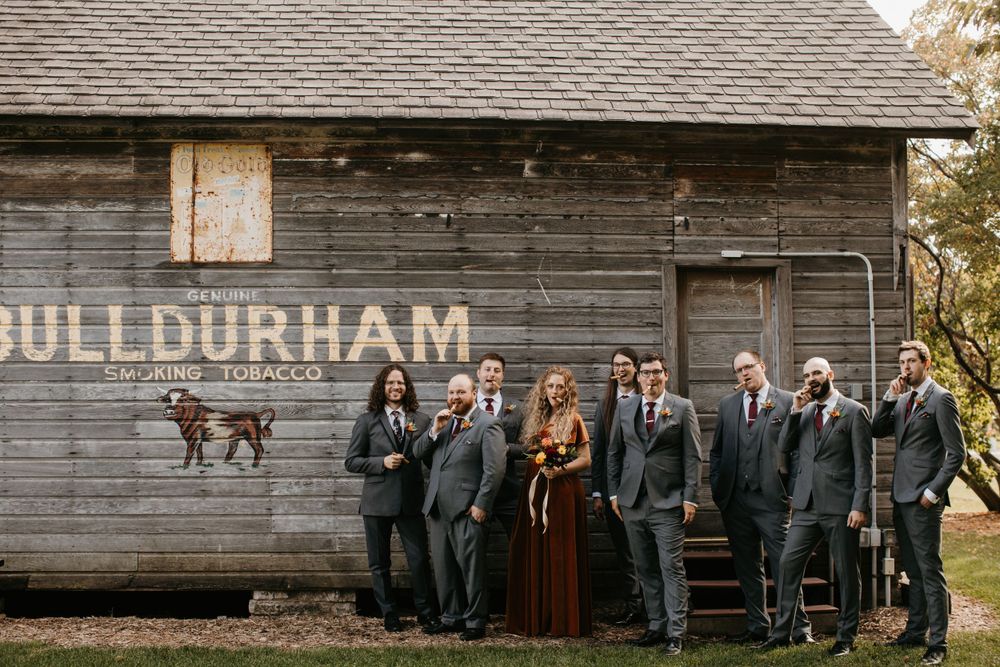 Wedding party posing in front of a vintage Bull Durham tobacco barn sign in fall.