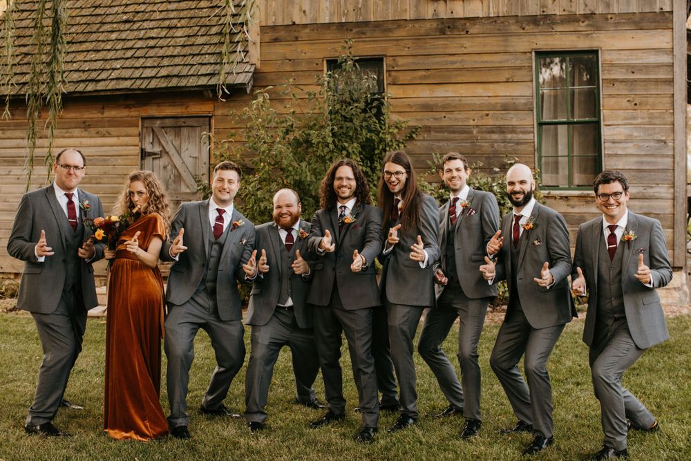 Groomsmen and bridesmaids celebrating with champagne flutes outside a rustic barn venue.