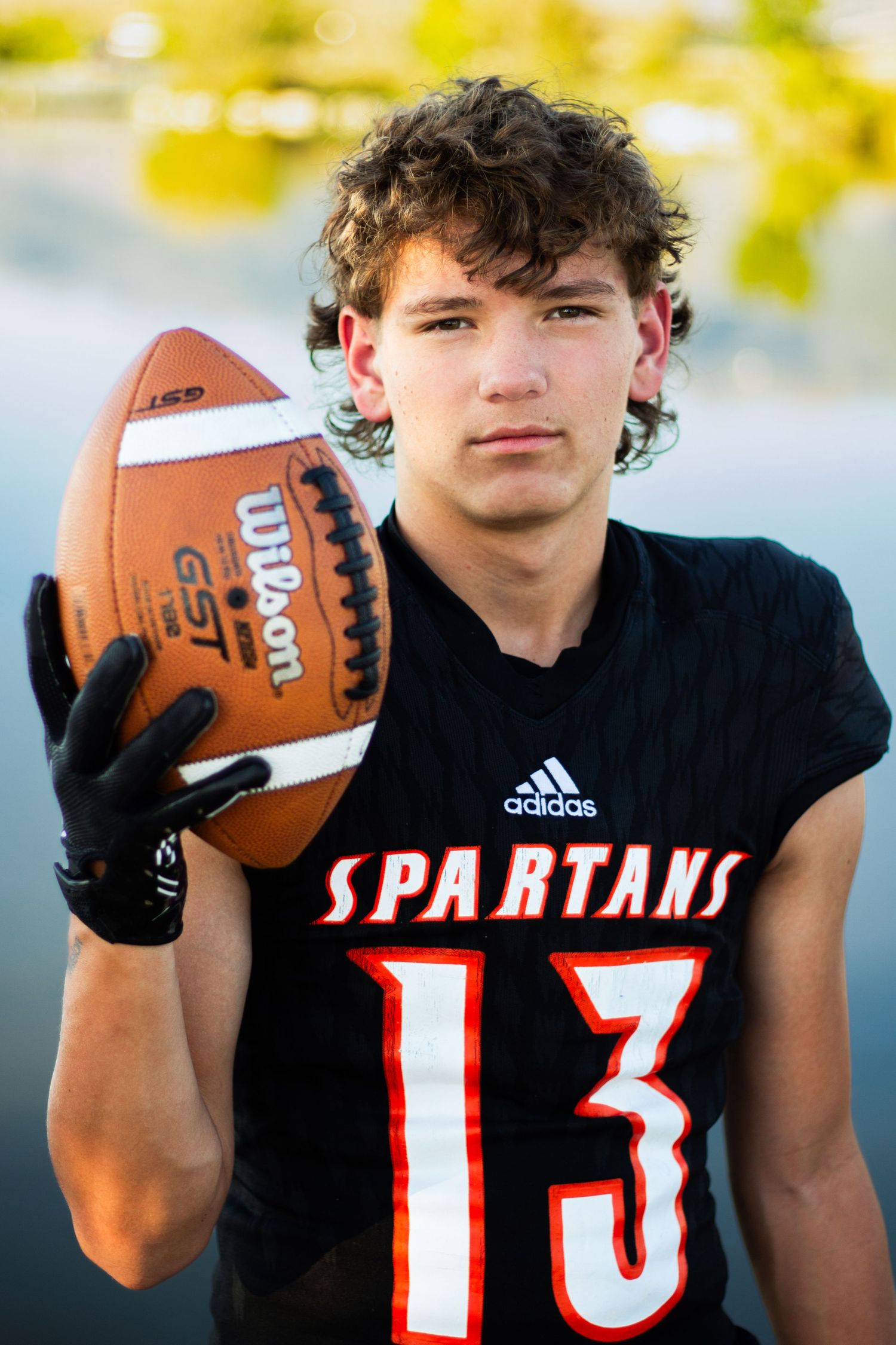 High school football player, posing with ball. Taken next to Bountiful pond in Utah.