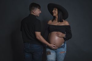 Maternity photo of couple in dark setting sharing intimate moment.