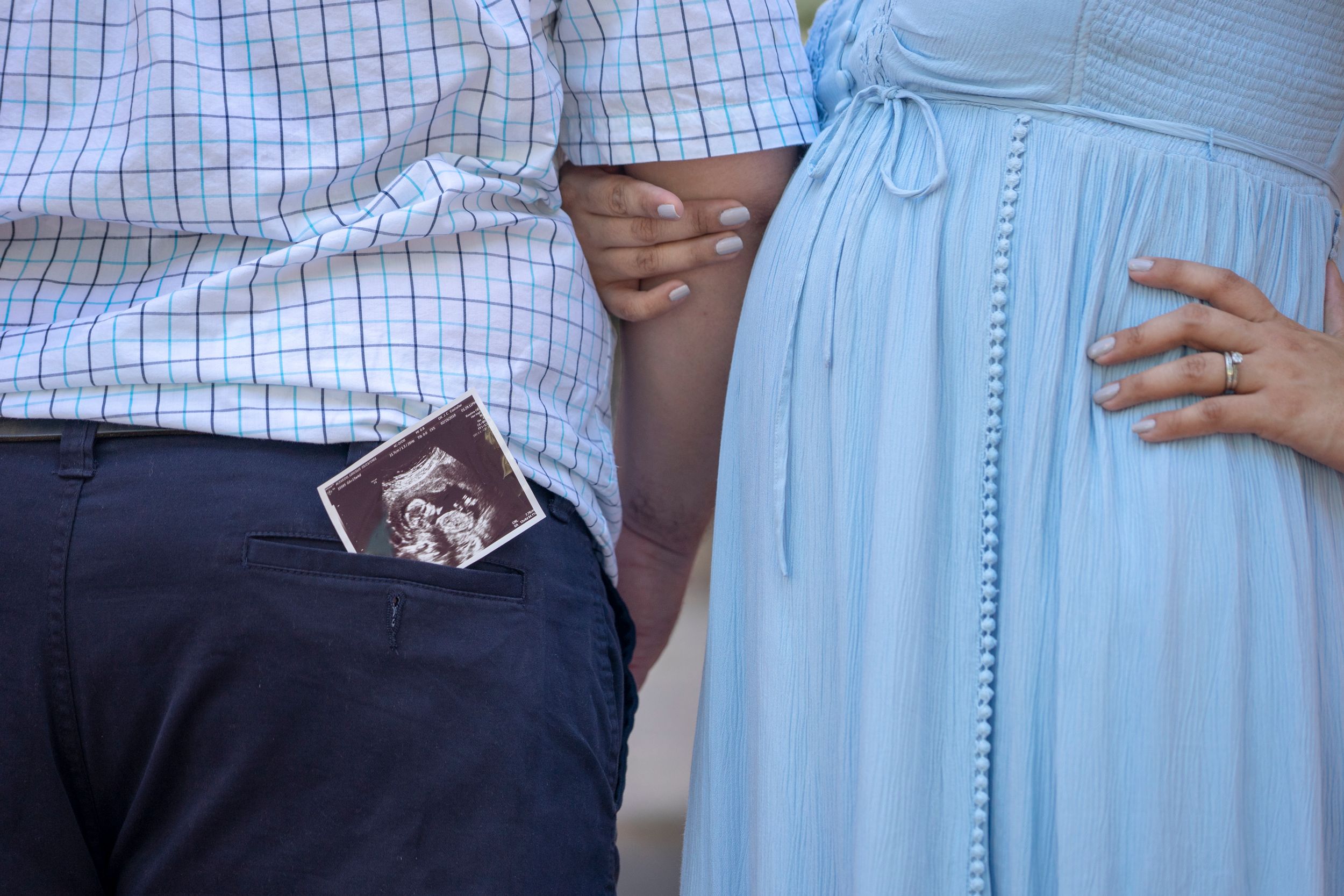 Close-up of couple holding ultrasound photo in casual attire.