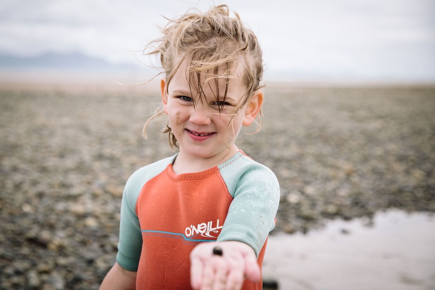 A joyful moment at the beach in a wetsuit on a cloudy day.