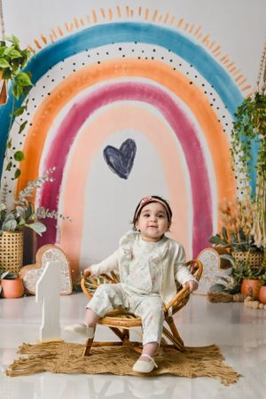 Rainbow painted wall backdrop with rattan chair setup for a boho-style photoshoot.