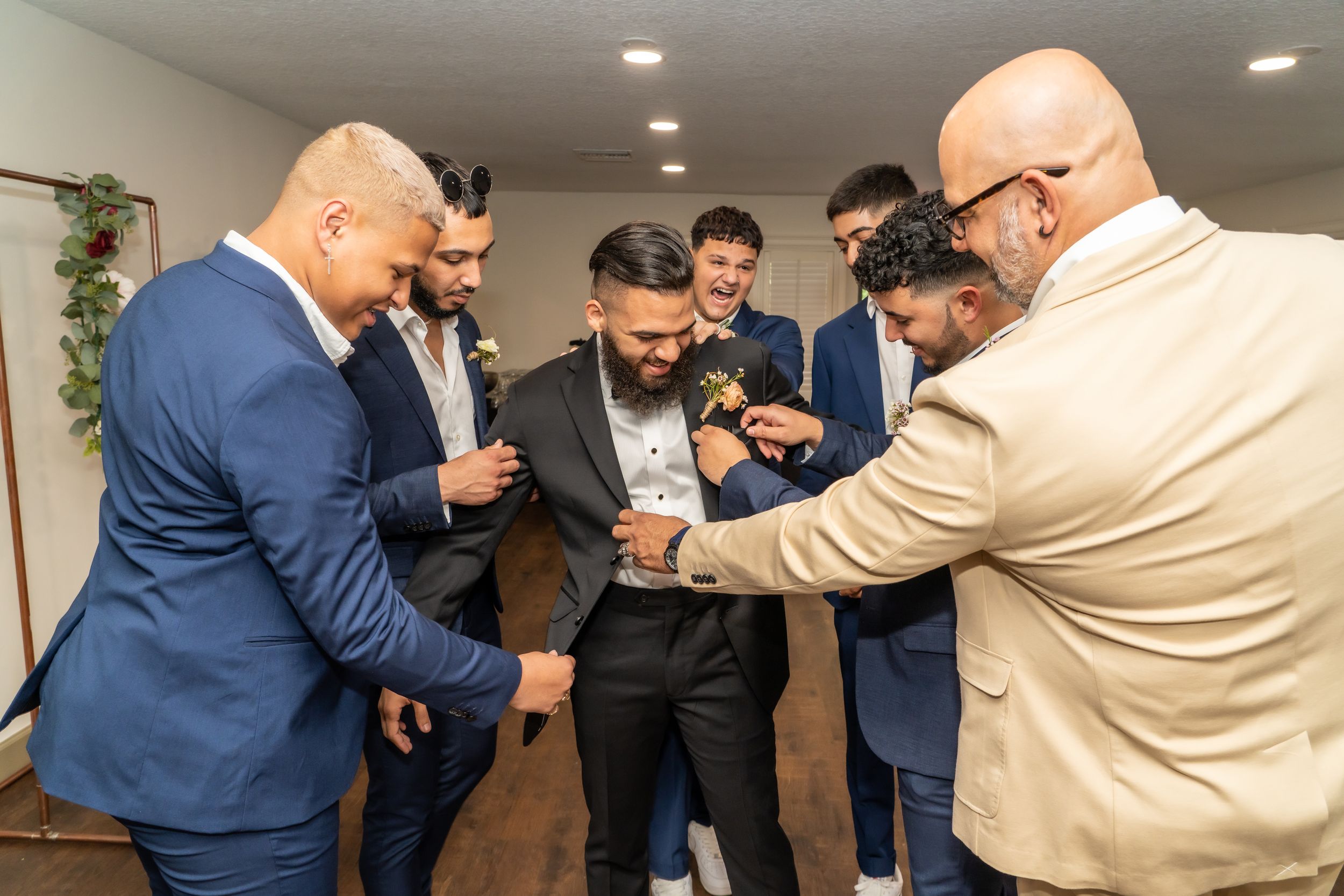 A group of men in formal attire gather around looking at something on a phone.