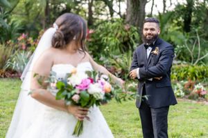 A candid wedding moment captured in a lush garden setting with floral bouquet.