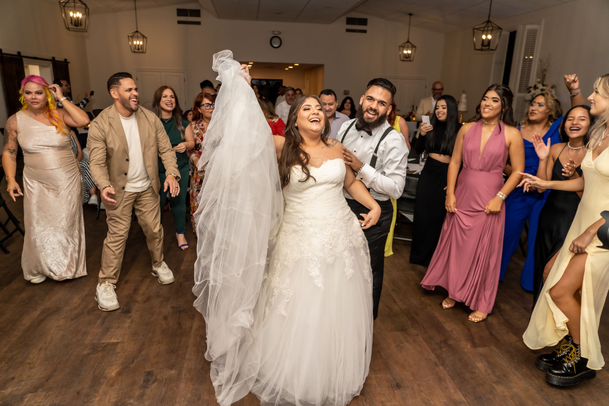 A joyous reception dance scene with guests celebrating in formal attire.