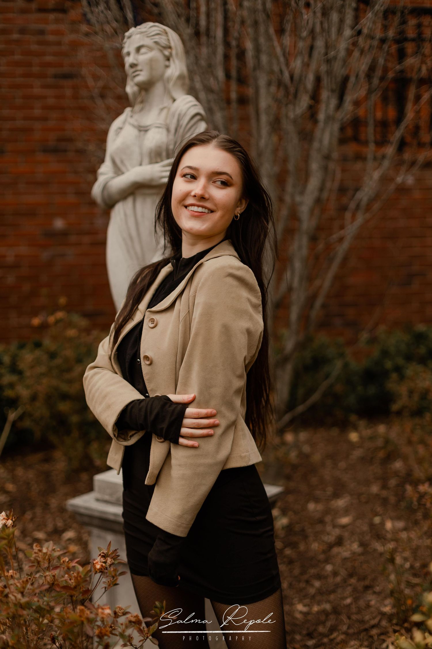 Stylish autumn portrait with architectural elements and a stone statue backdrop.