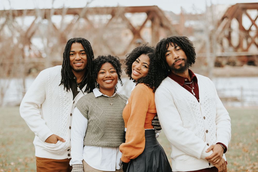 A group in coordinating neutral outfits poses together outdoors during a winter photoshoot.