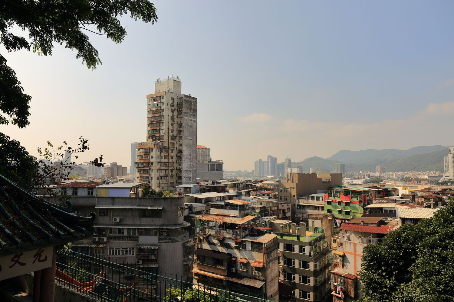 Urban cityscape view of Macau with residential buildings and mountains in background.